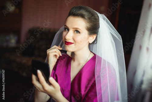 Beautiful young bride with wedding makeup and hairstyle in bedroom  attractive newlywed woman have final preparation for wedding. Happy Bride waiting groom. Marriage Wedding day moment. Bride portrait