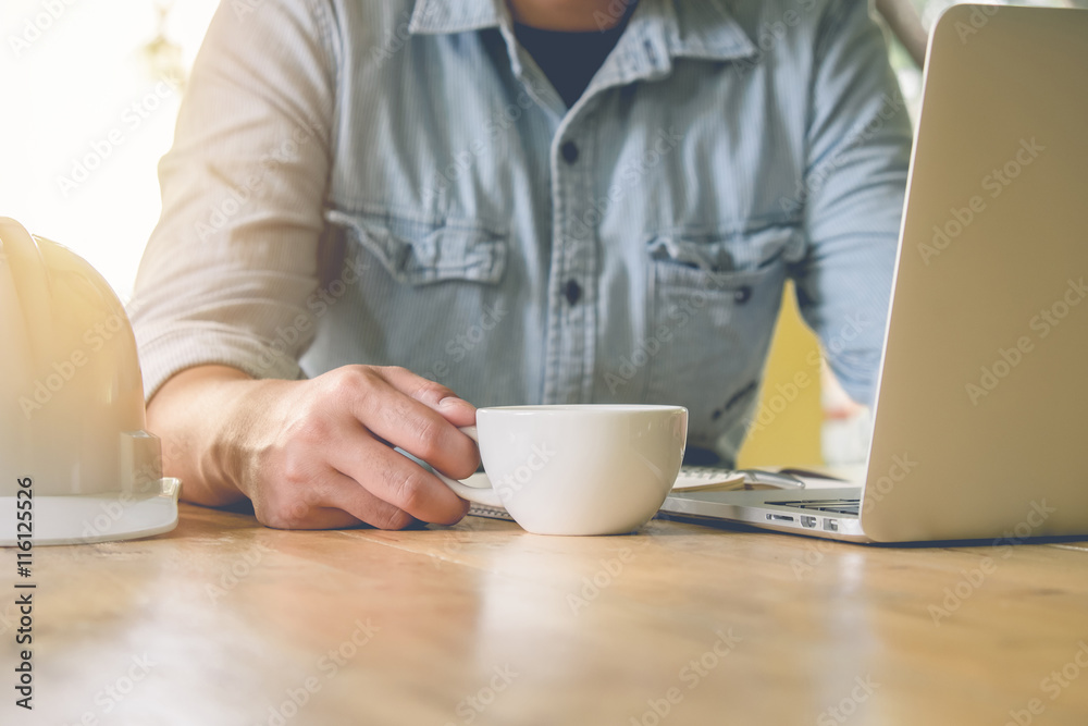 Business man holding a cup of coffee and using laptop, on wooden Business man holding a cup of coffee and using laptop, on wooden