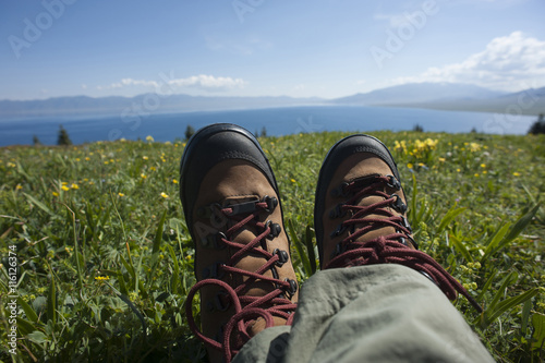 hiker sitting on a grass mountain top with first person perspective view
