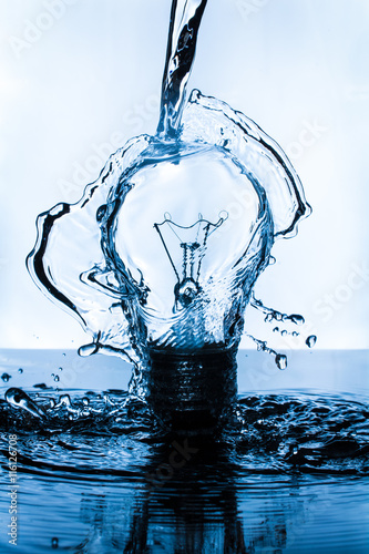 Lightbulb splashed with water on dark surface with blue hue
