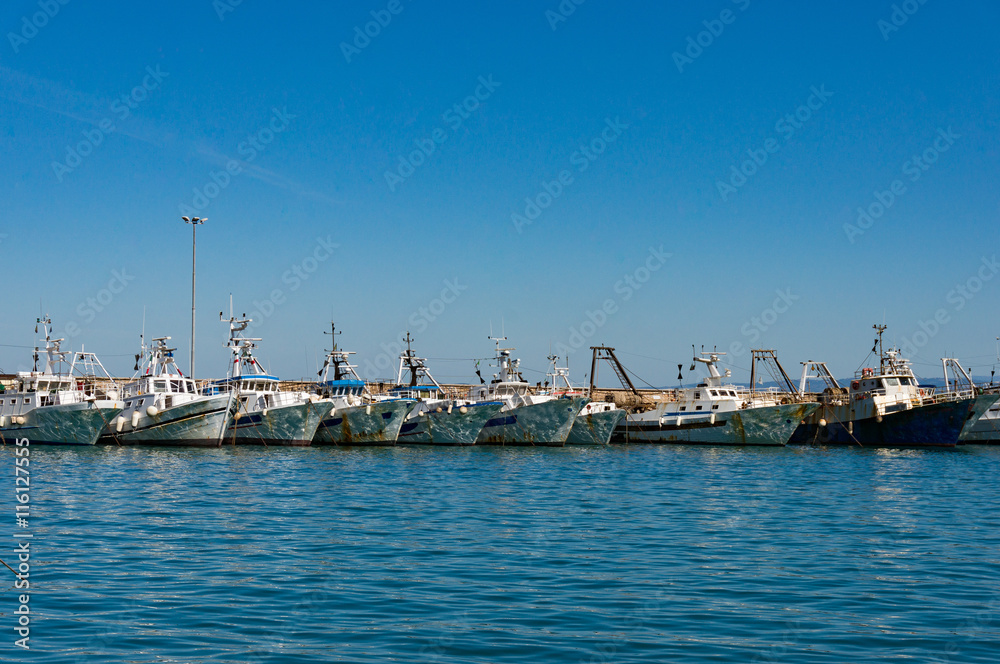 Boats, yachts on turquoise blue water with sun specks, reflections on boards against clear blue sky on the background. Summer vacation scene with copy space