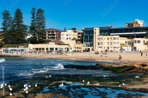 Sunny day on Cronulla beach. Urban beach with sand shore with and unidentified people and water view property on the background. Cronulla, NSW, Australia photo