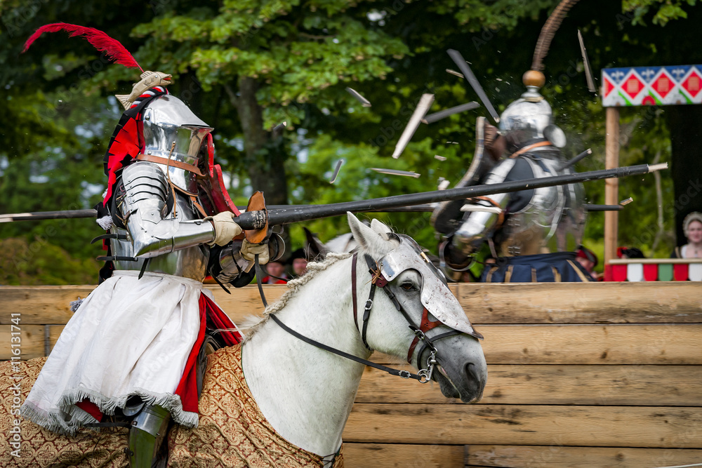 Armored knights on horseback charging in a joust right after the impact . Jousting is a martial game or hastilude between two horsemen wielding lances with blunted tips, often as part of a tournament.