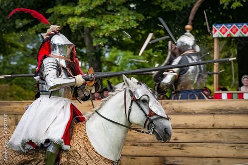 Armored knights on horseback charging in a joust right after the impact . Jousting is a martial game or hastilude between two horsemen wielding lances with blunted tips, often as part of a tournament. © Victor Moussa