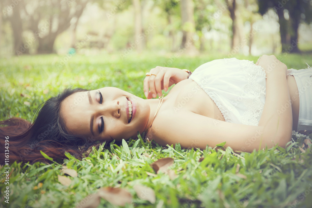 Young happy and smiling woman laying down on green grass (Vintage tone) Young happy and smiling woman laying down on green grass (Vintage tone)