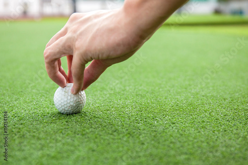 Golfer putting a golf ball onto green grass field