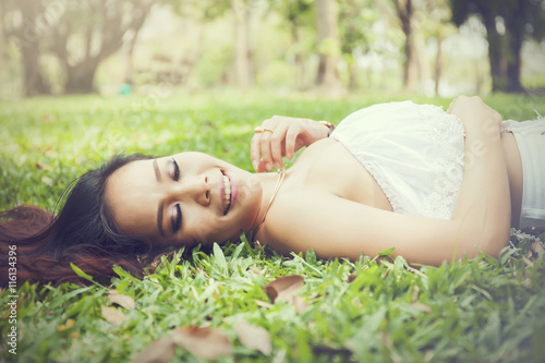 Young happy and smiling woman laying down on green grass (Vintage tone)
