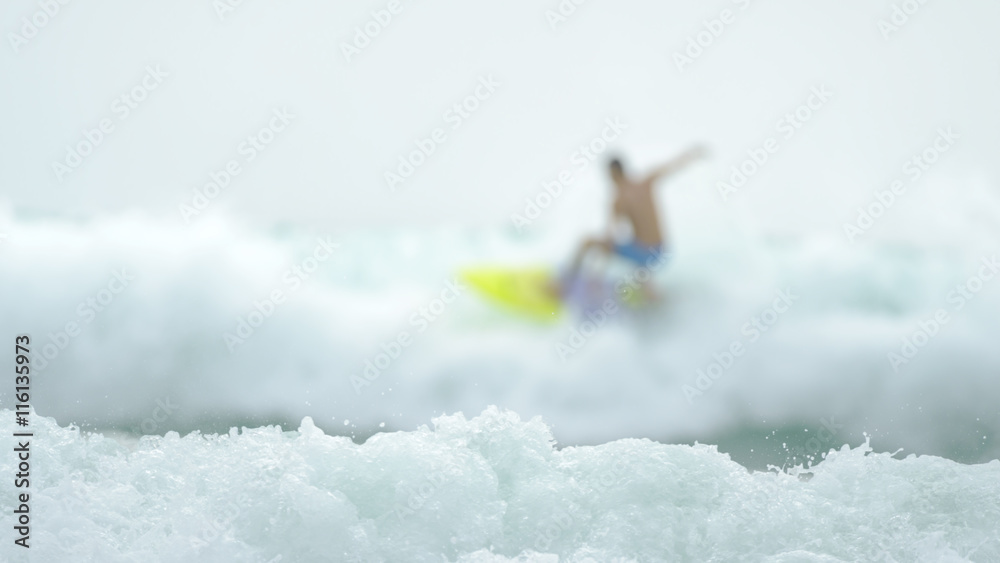 Naklejka premium Defocus surfer enjoys the waves