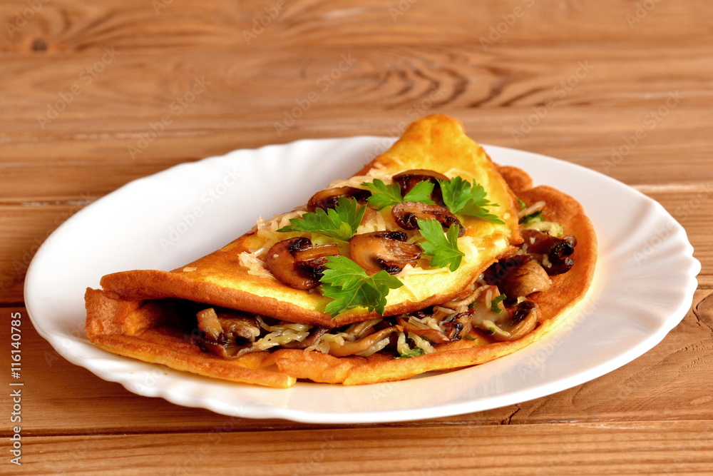 Omelet with grated cheese, fried mushrooms and fresh chopped parsley on a plate and on wooden table. Healthy breakfast recipe with eggs for kids, for family Omelet with grated cheese, fried mushrooms and fresh chopped parsley on a plate and on wooden table. Healthy breakfast recipe with eggs for kids, for family