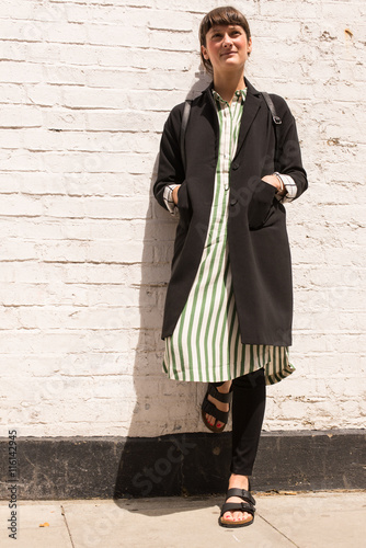 Hipster woman dressed in urban minimal style with long black jacket and striped dress © drimafilm