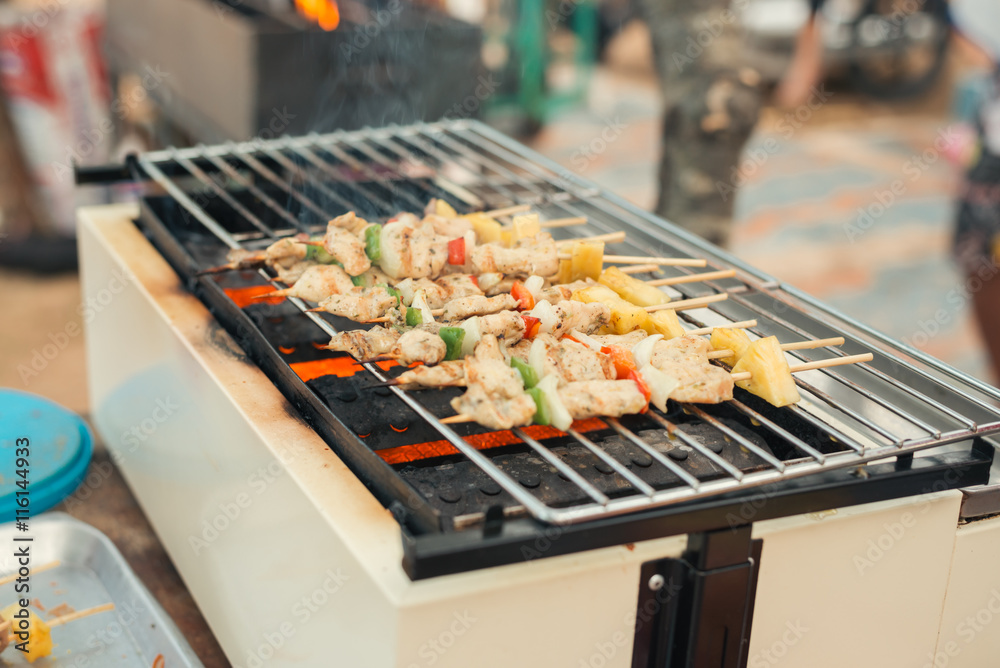 Assorted meat from chicken and pork and various vegetables on barbecue grill cooked for summer family dinner