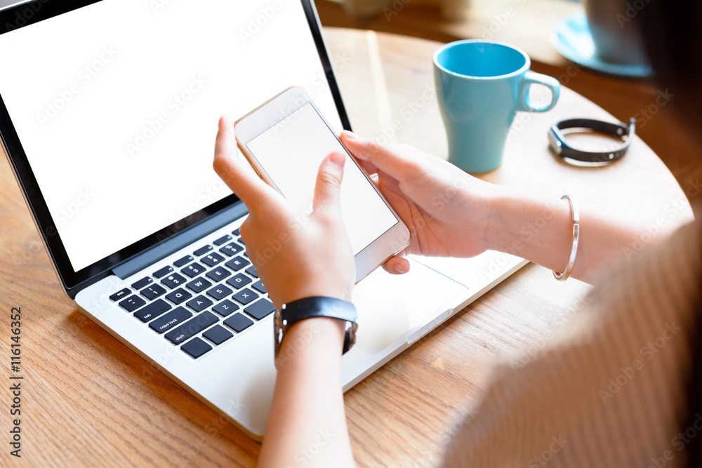 A young woman using smartphone and laptop in cafe. A young woman using smartphone and laptop in cafe.