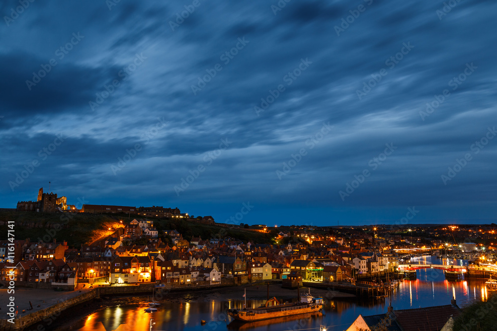 WHITBY, ENGLAND - JULY 16: Whitby Abbey, with harbour in foreground, at night. In Whitby, North Yorkshire, England. On 16th July 2016.