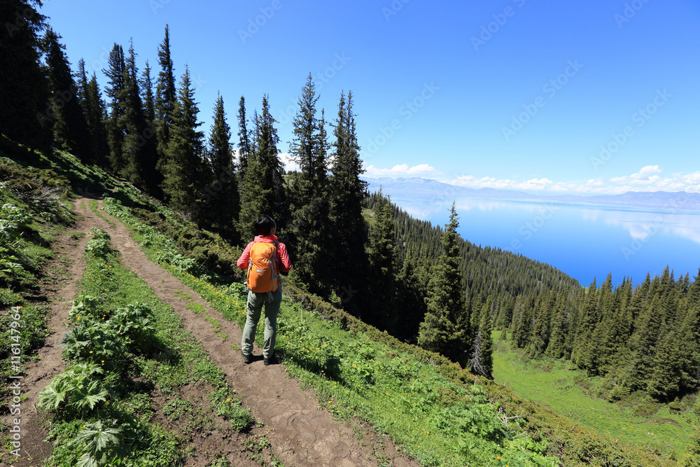 young woman backpacker hiking on beautiful mountain peak trail