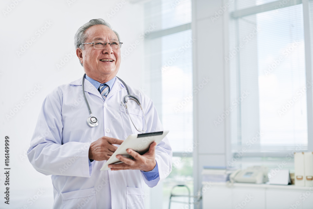 Aged Asian doctor using digital tablet in clinic Aged Asian doctor using digital tablet in clinic