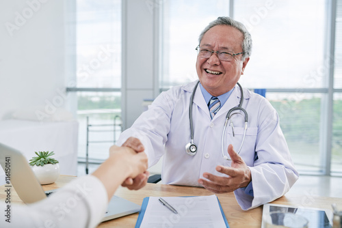 Vietnamese aged doctor greeting his patient before check-up