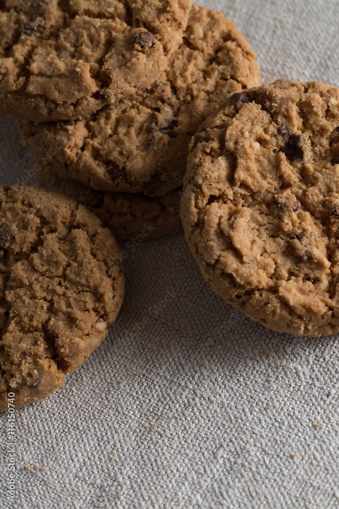 Cookies pile with chocolate chip on light textile background. Delicious morning snacks for breakfast, brunch and lunch. Appetizing, healthy, sweet, scrummy, and fast food.