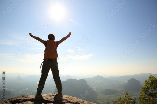 cheering woman hiker at sunrise mountain peak