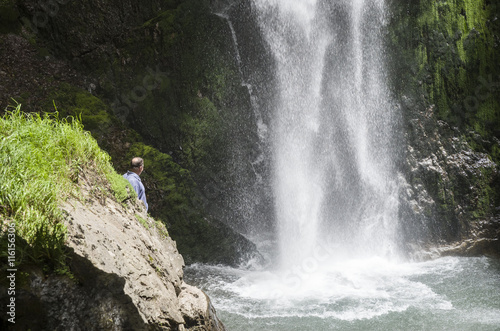 Man looking out the spray of a waterfall