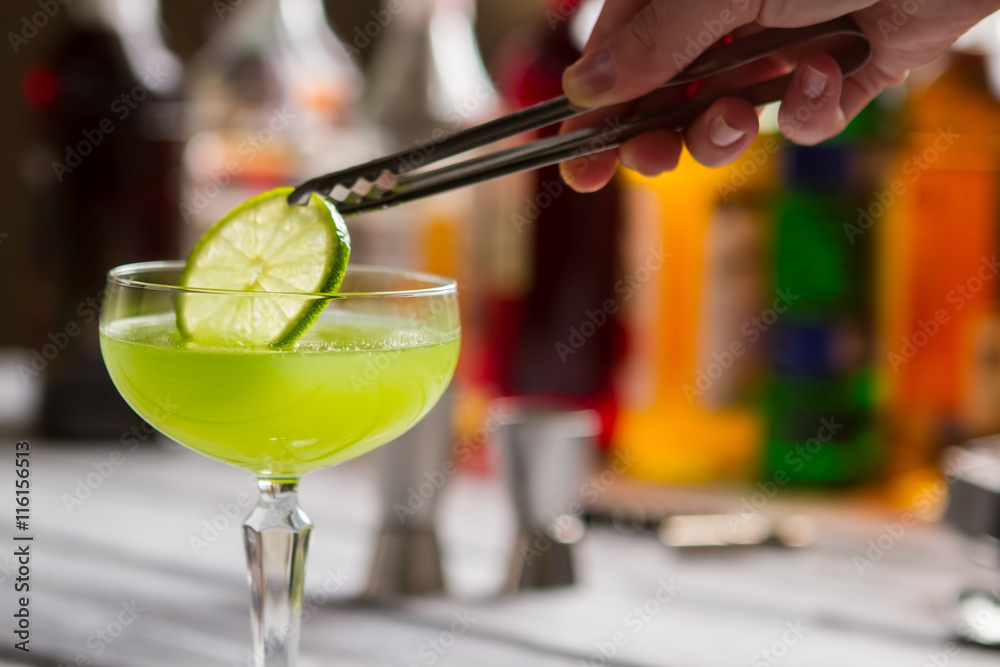 Green drink in coupe glass. Tongs hold slice of lime. Delicious beverage  with sour juice. Fresh taste of kiwi daiquiri. Stock Photo | Adobe Stock