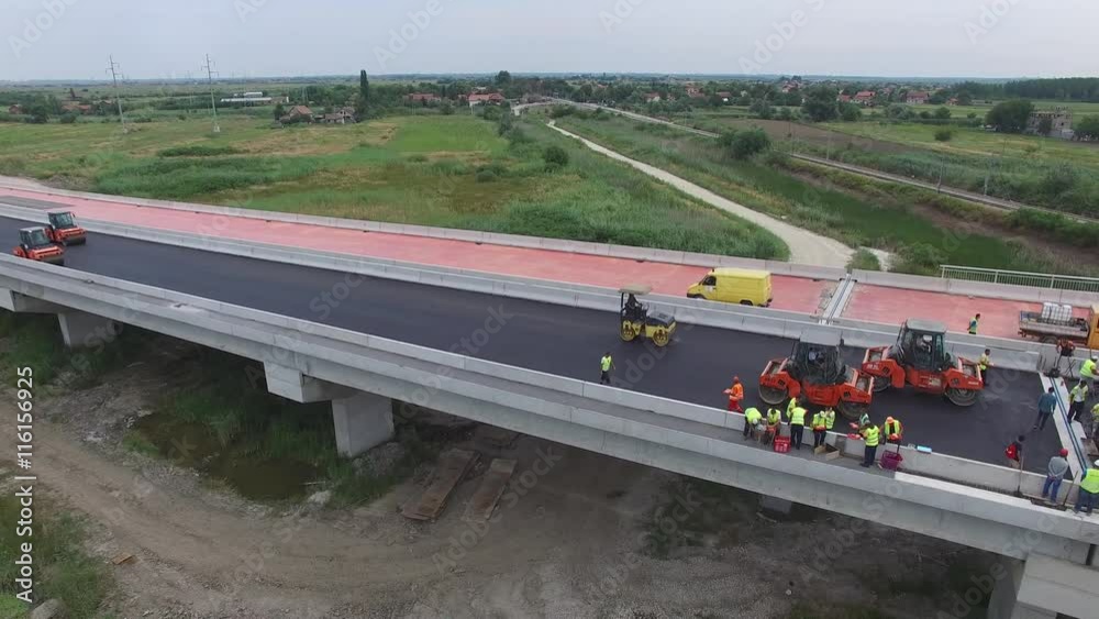 Aerial view on workers with heavy machines working on bridge reconstruction.
