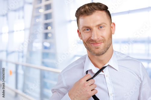 Confident young man in shirt and tie  adjusting his necktie
