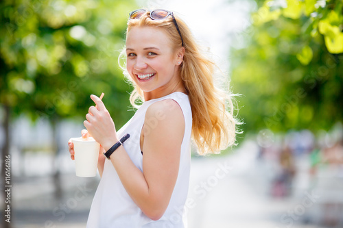 Cute blonde holding milkshake and showing tongue