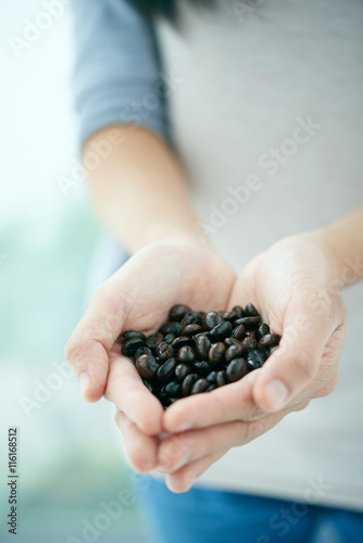 Cropped image of person with handfuls of roasted coffee beans