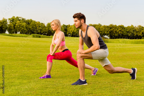 Sportive man and woman doing stretching exercises in the park