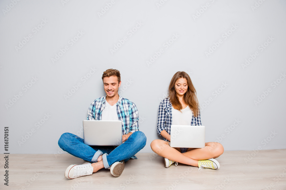 Man and woman sitting on floor with laptops and chatting Man and woman sitting on floor with laptops and chatting