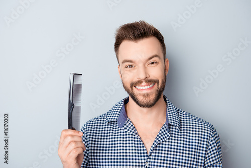 Happy guy with beaming smile and healthy hair holding comb