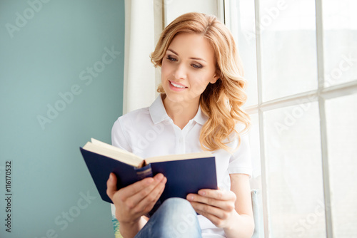  beautiful smiling relaxed woman reading book near window