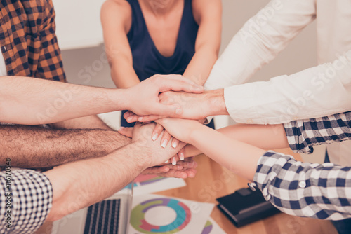 Close-up of business partners making pile of hands at meeting