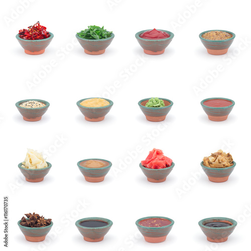 Different sauces (soy, chilli, wasabi, ginger, ketchup, mustard) in a clay sauce-boat isolated on white background