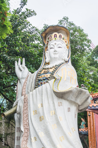 White statues of Kwun Yam with green leaves and bright sky as background at Kwun Yam temple in Hong Kong.