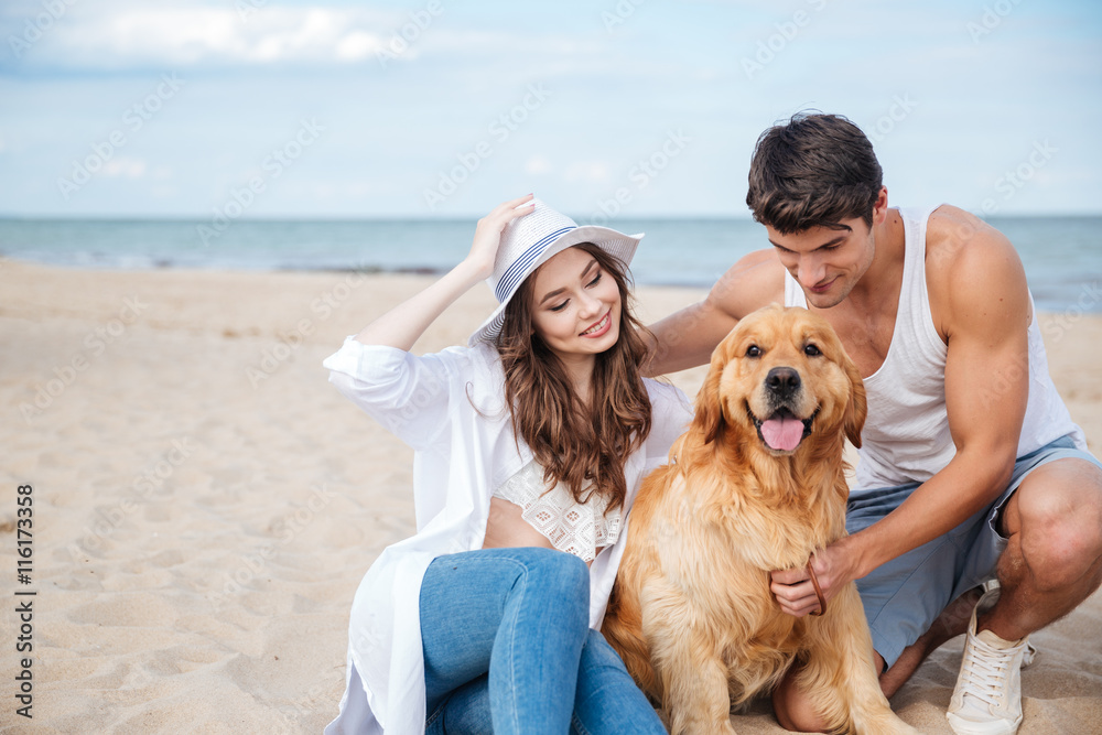 Young loving couple playing with their dog at the seaside Young loving couple playing with their dog at the seaside