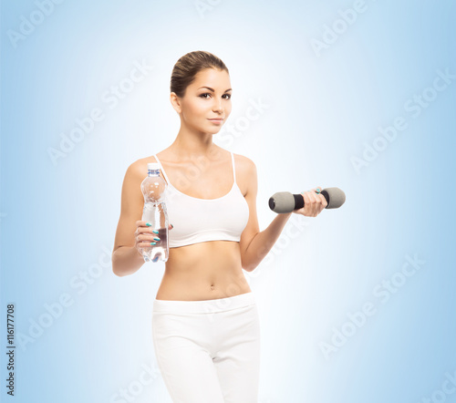 Young and fit woman holding a bottle of water and a dumbbell