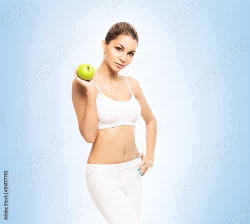 Young and fit woman in sporty clothes holding an apple
