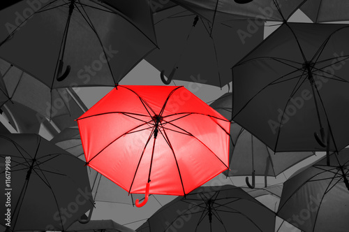 Red umbrella in black and white umbrellas