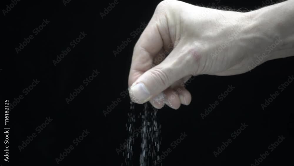 Hand salts food on a black background. Slow motion, high speed camera, 250fps