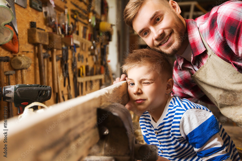 father and little son with wood plank at workshop father and little son with wood plank at workshop