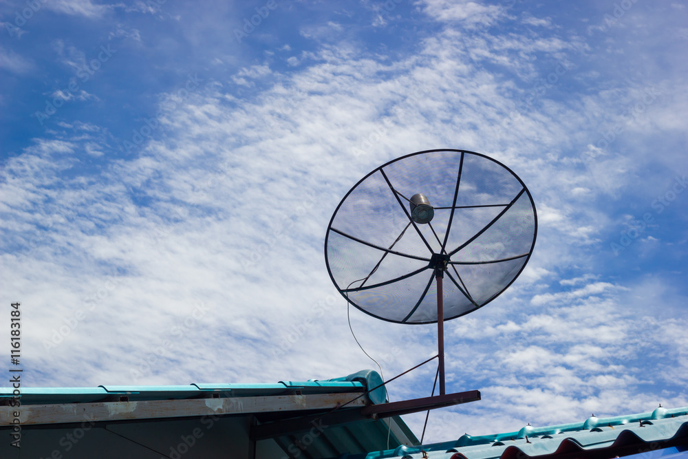 Satellite dish on the roof in the cloudy blue sky.