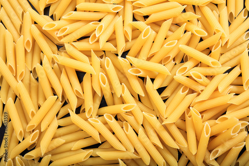 Full background of raw penne pasta