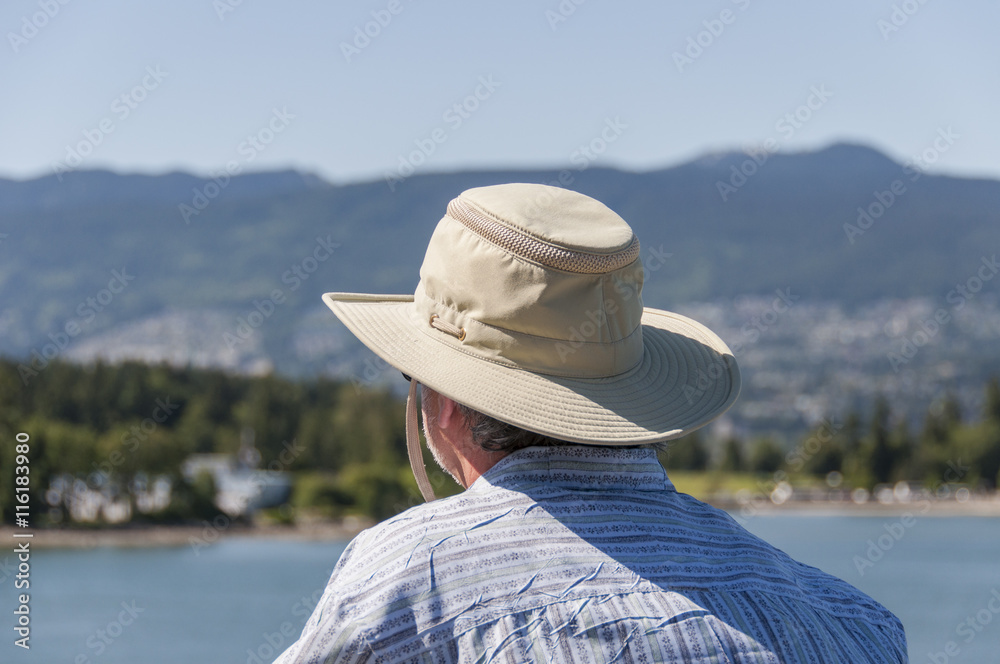 Middle-aged man with a hat looking far at the horizon
