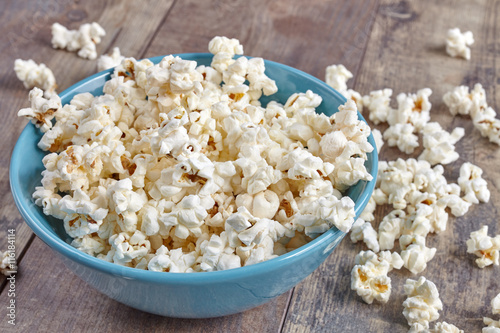 Blue bowl with popcorn on wooden background