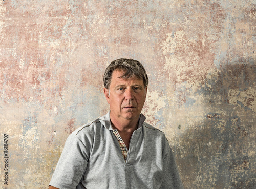 portrait of senior man in front of grungy old wall