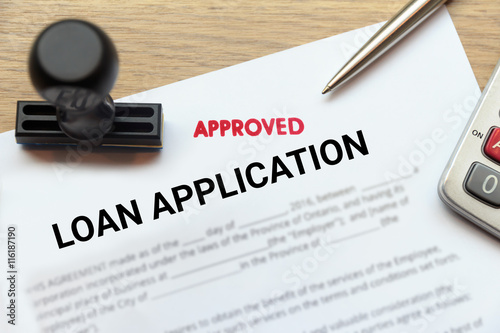 Approved loan application form lay down on wooden desk photo