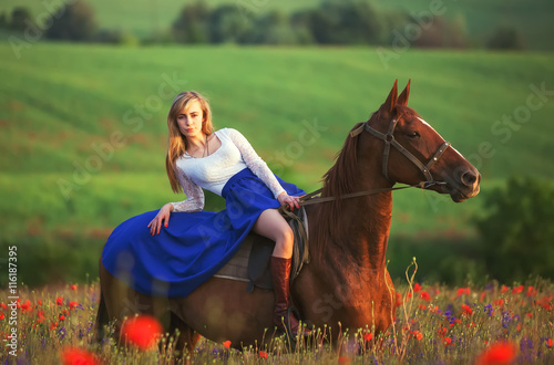 Beautyful blonde woman with horse on a flover field