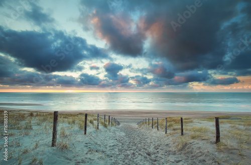 sunset over North sea beach and sand path on dunes