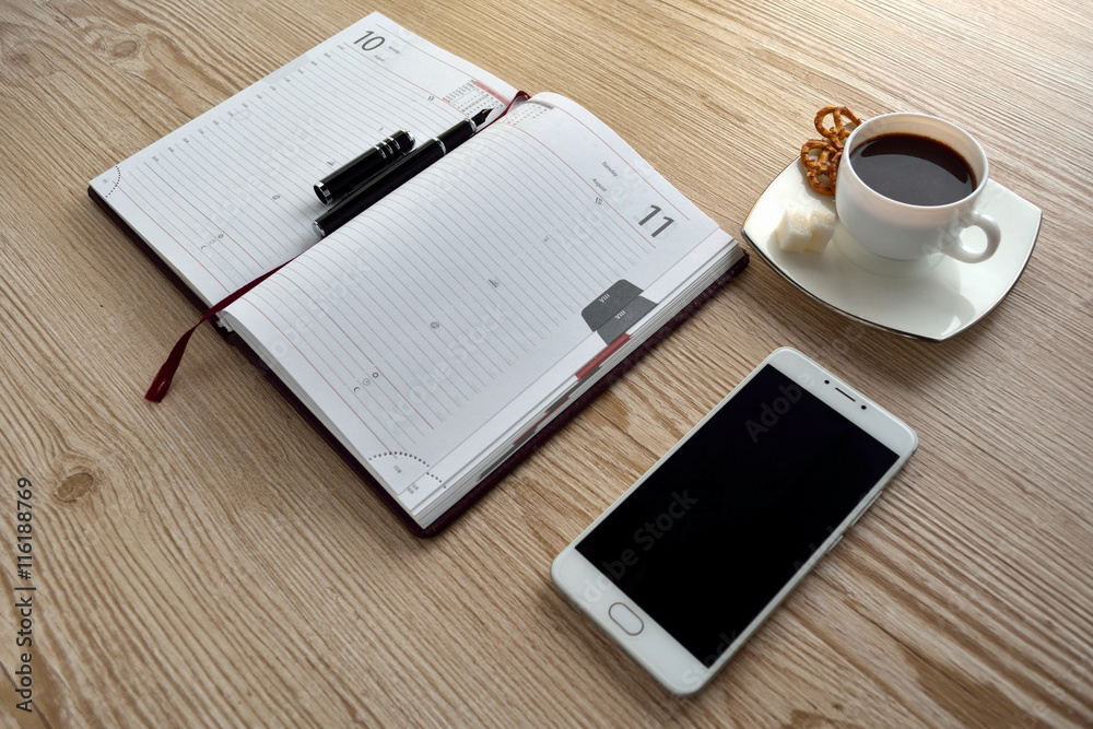 Open notebook with cup of coffee on wooden desk Open notebook with cup of coffee on wooden desk